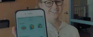 smiling woman holding a phone with picmonic app open